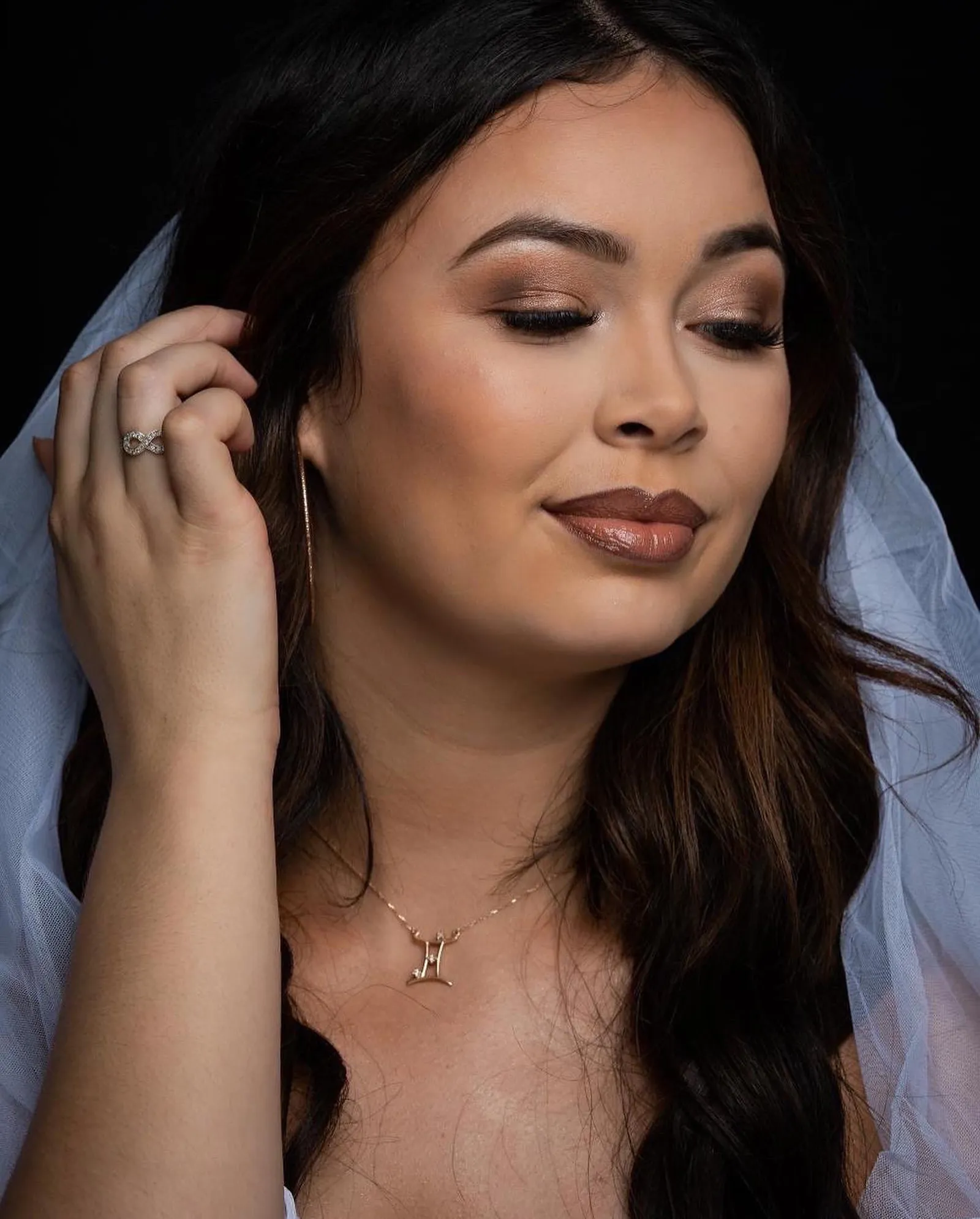 A bride under a soft veil with a warm bronze eye and a glossy nude lip